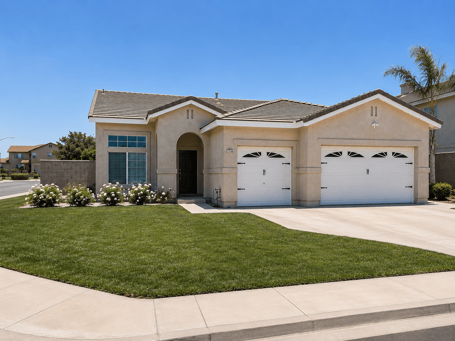 Single-story beige house with a three-car garage, green lawn, and white rose bushes.
