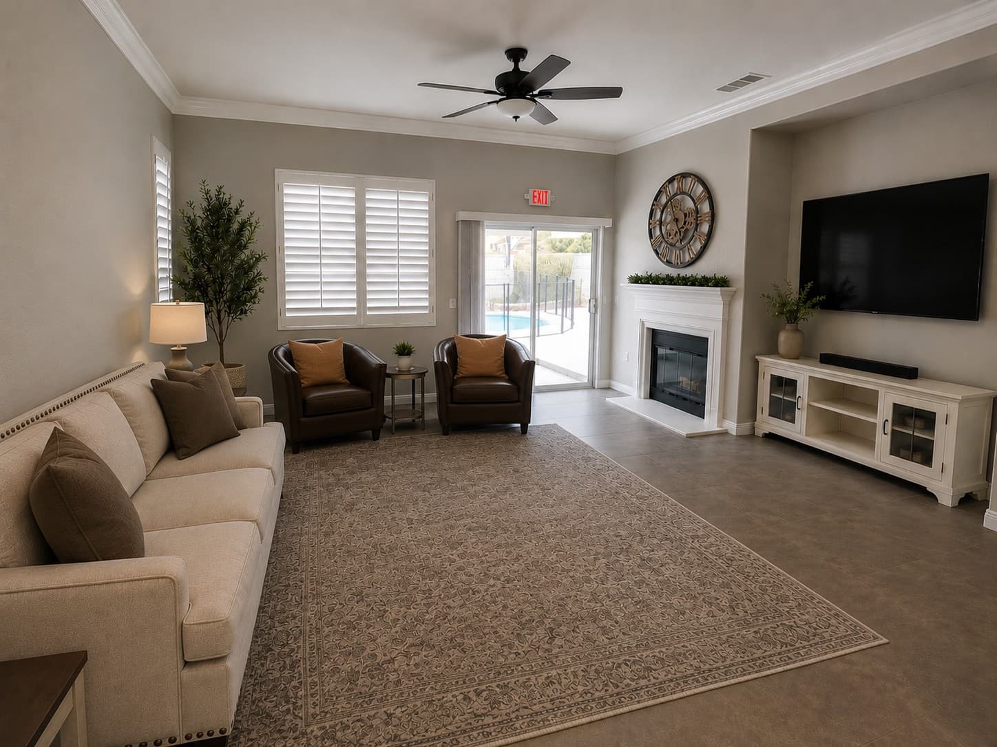 Neutral living room with a beige sofa, leather armchairs, fireplace, and large patterned rug.